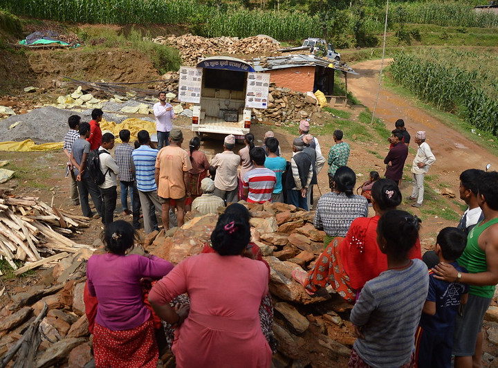 A group of people with their back to the camera attend a community meeting