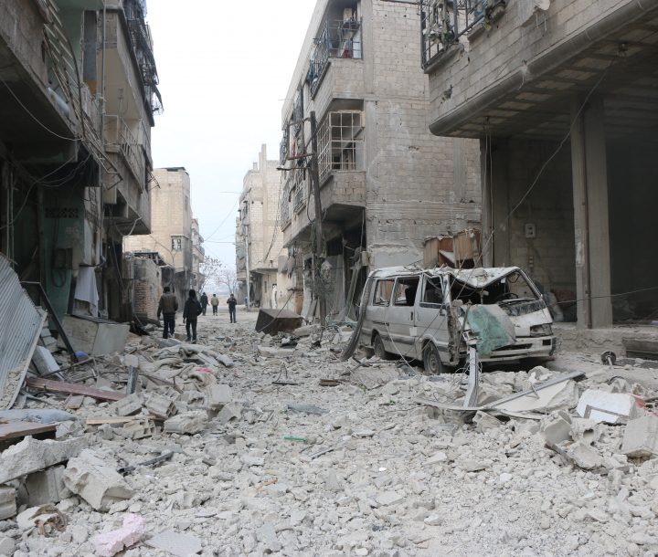 A street covered in rubble with damaged buildings lining either side