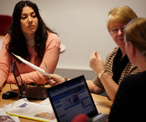 Three women sit at a table talking.