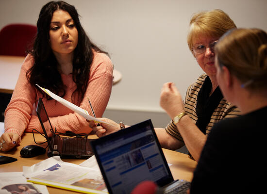 Three women sit at a table talking.