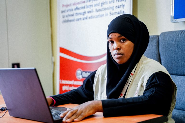 An early childhood educator sits at a computer in an office in Somalia