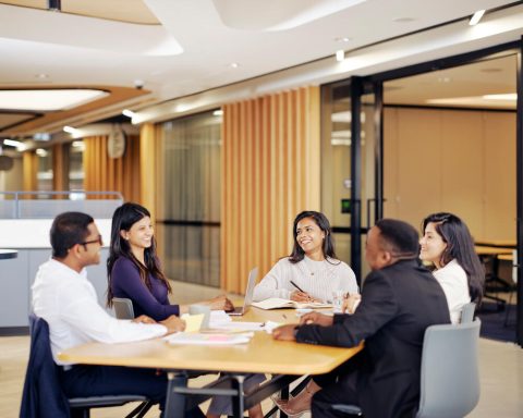 Five people sit in a u-shape around a table.