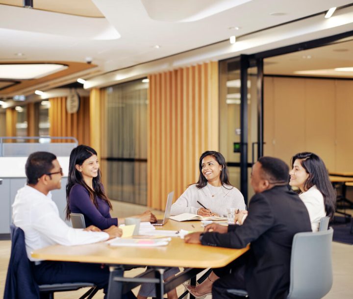 Five people sit in a u-shape around a table.